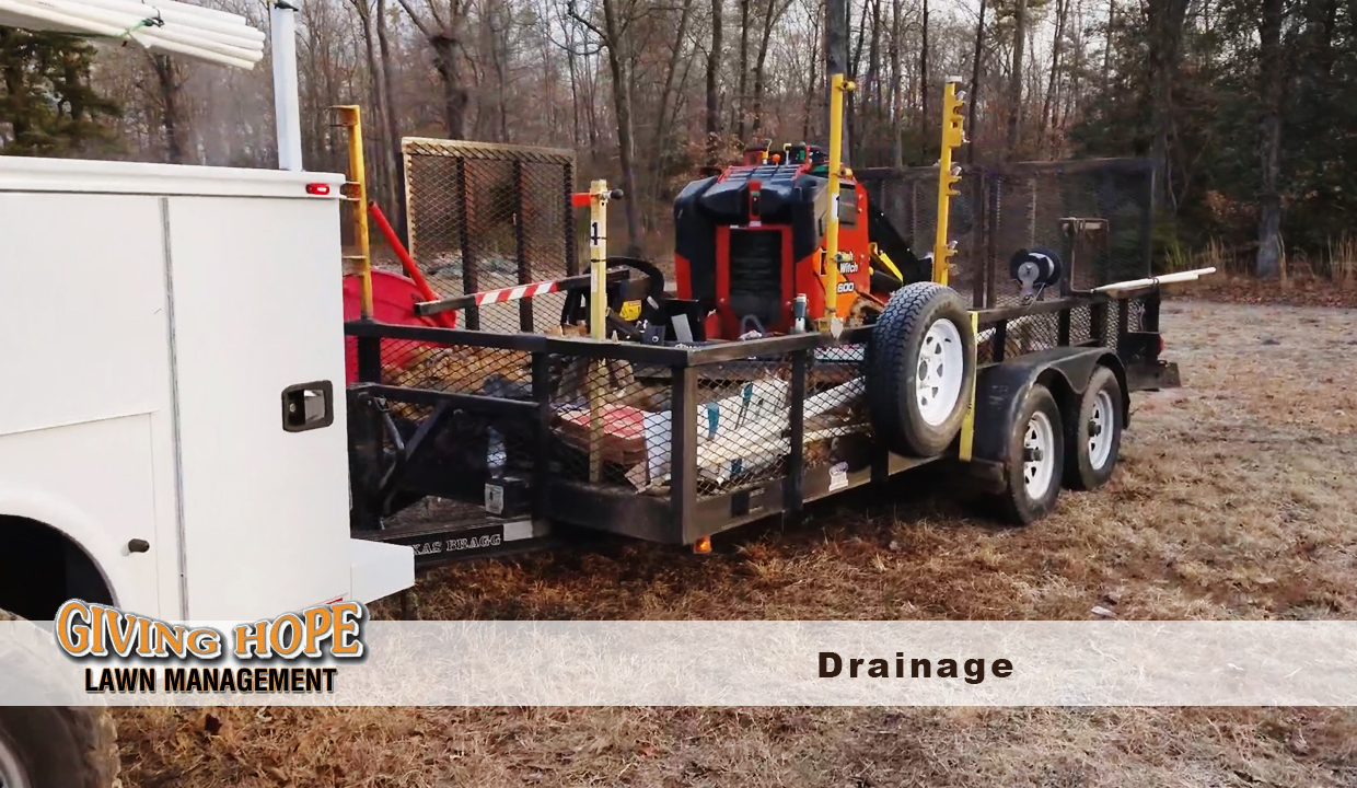 Giving Hope Lawn Management truck and trailer loaded with drainage installation equipment