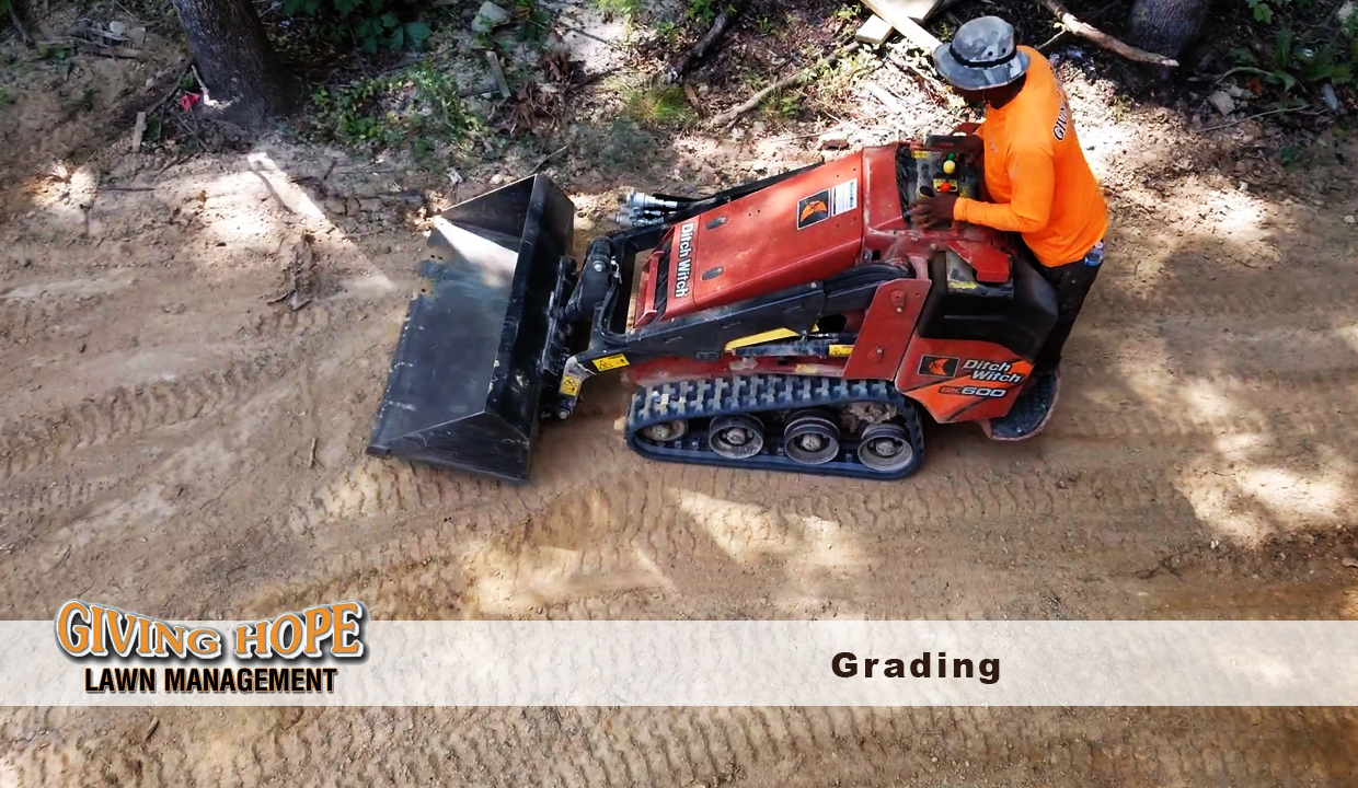 Giving Hope Lawn Management operator grading soil with a compact track loader