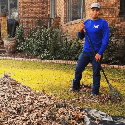 Macario Brothers worker raking fallen leaves from a front yard