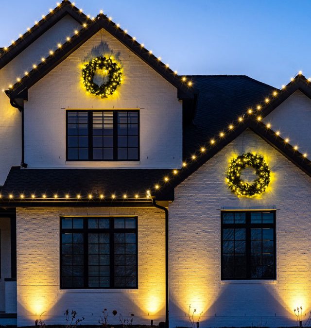 Neighboring homes on a suburban Alabama street at dusk, one with a JellyFish roofline in warm white installed by New Age Lights and one unlit