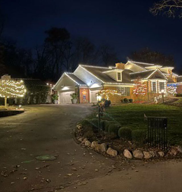 Split view of a Vestavia Hills two-story home: seasonal C9 roofline lights on one side, permanent color-matched track lit red and green on the other