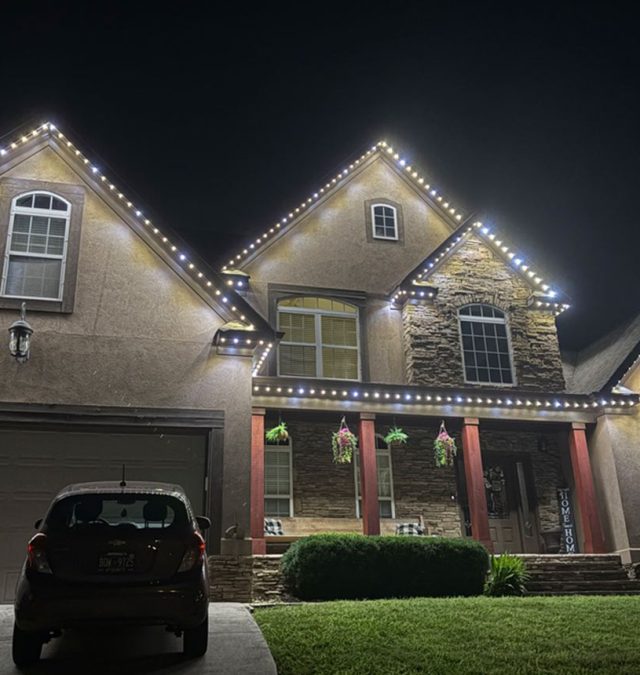 Close-up of a color-matched permanent lighting track seated under the drip edge on the painted wood fascia of a slate-roofed Homewood, AL home, shingles untouched