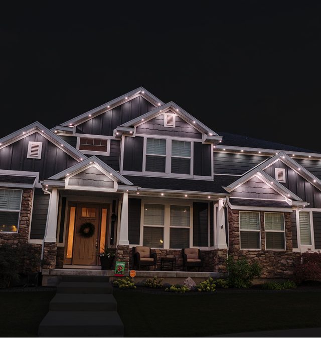 New Age Lights crew working from a lift on a two-story Ooltewah home with a walkout rear, C9 warm white roofline lit