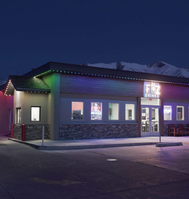 Evening view of a Hyde Park, Cincinnati brick home with permanent roofline lighting in warm white along the fascia beneath a slate roof, installed by New Age Lights