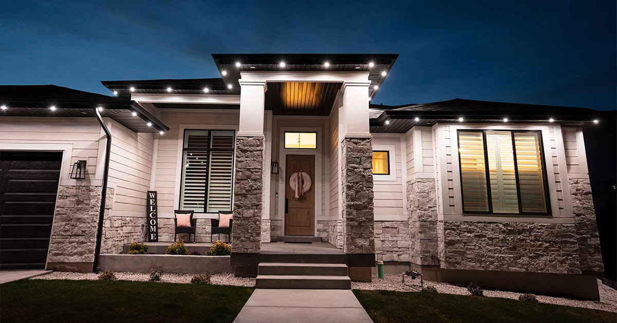 Modern single-story home at dusk with white permanent lighting along the rooflines and front entry