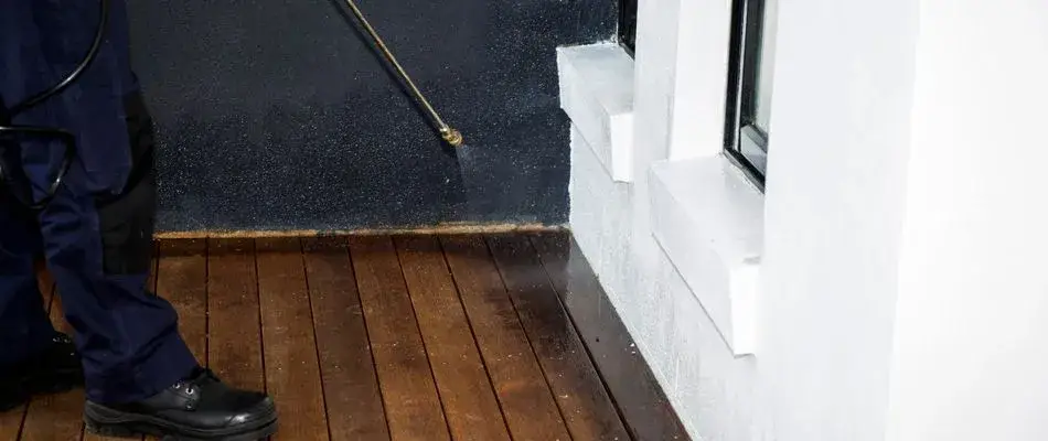 content technician spraying perimeter pest control to home 1920w