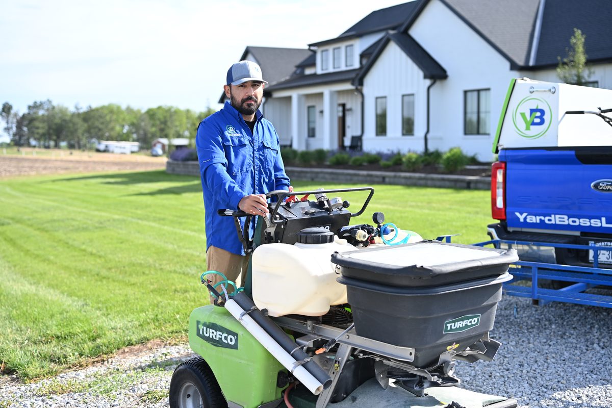 Yard Boss technician with a Turfco spreader sprayer ready for fall lawn fertilization at a home near Lincoln, NE