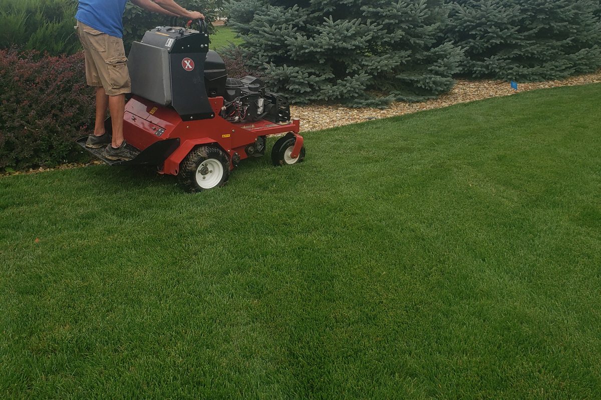 Yard Boss technician core aerating a Lincoln area lawn with a stand-on aerator