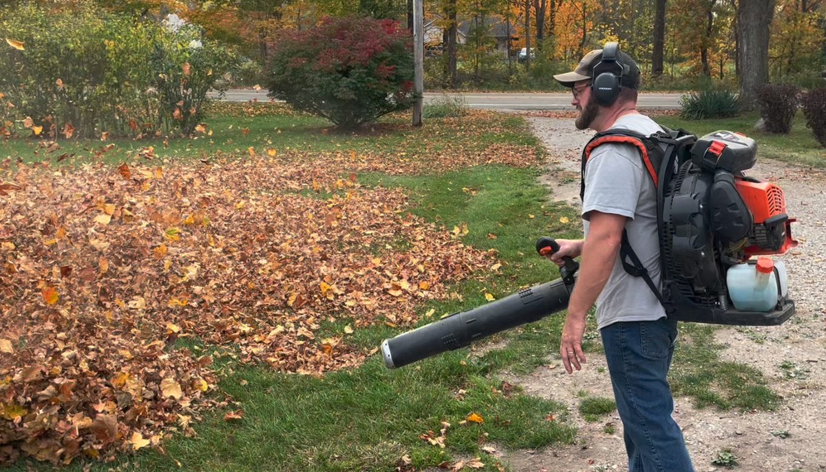 A Keast Lawn and Snow technician clearing fall leaves with a backpack blower in Michigan