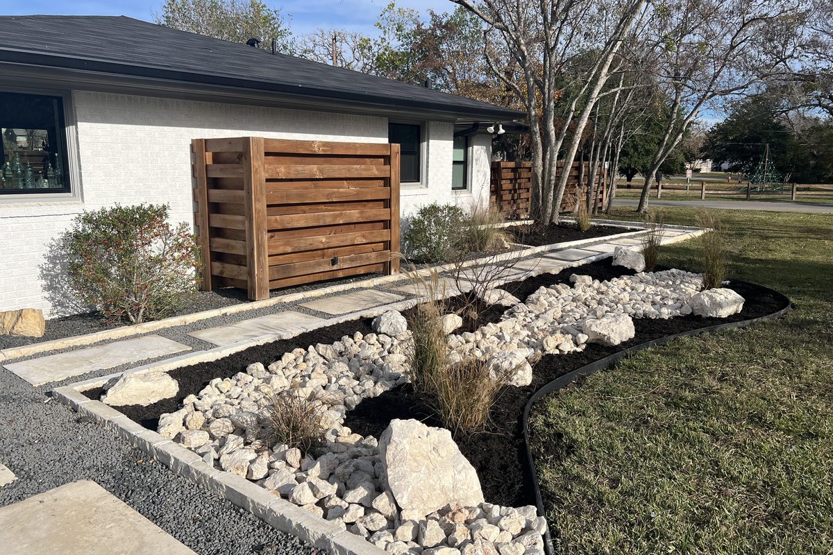 A finished residential xeriscape landscape installation with stone, rock beds, and native plantings