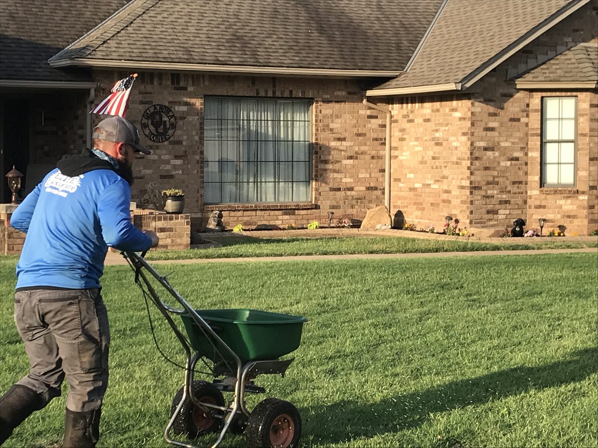 An Elite Lawn Care technician treating a lawn to control common Oklahoma weeds