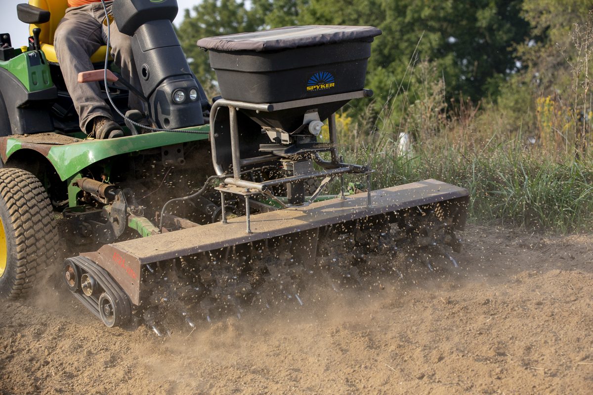 A tractor-mounted aerator opening up compacted soil on a Princeton area lawn
