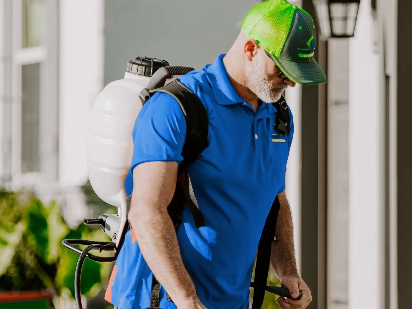 Complete Lawn Care technician with a backpack sprayer treating around a home's front door