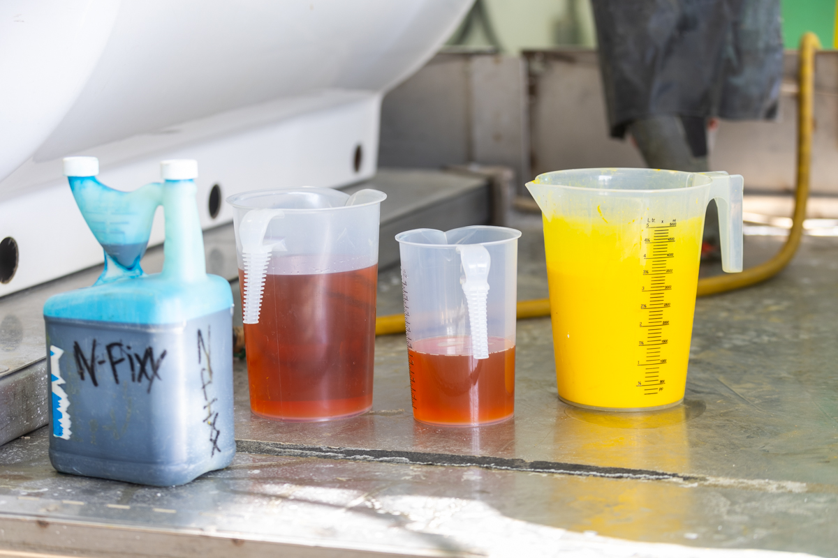 Measuring pitchers of amber and yellow liquid beside a jug labeled N-Fixx