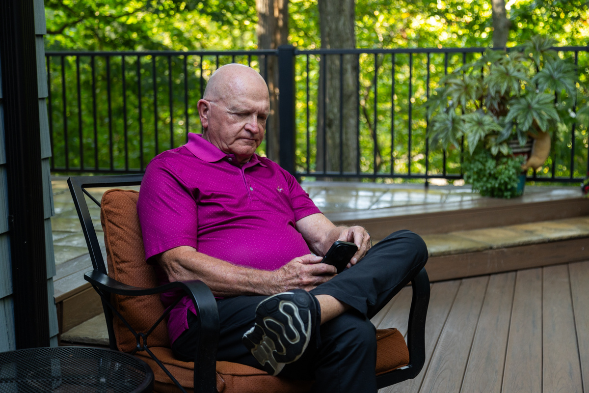 Man sitting in a deck chair, looking down at his phone