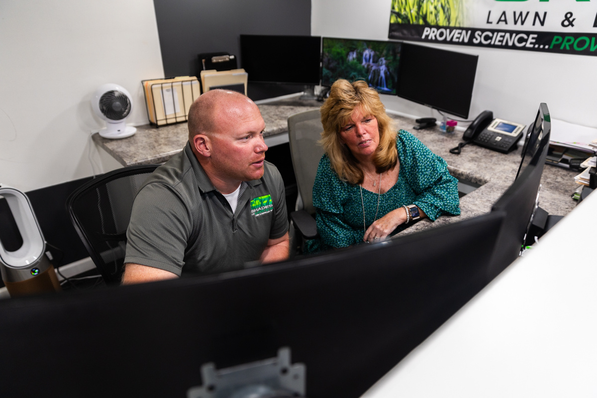 Two Shades of Green team members looking over details on an office monitor