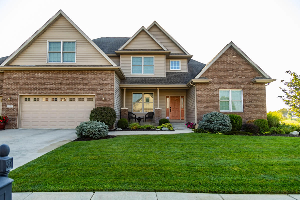 Two-story brick and beige-sided home with a green, neatly edged front lawn