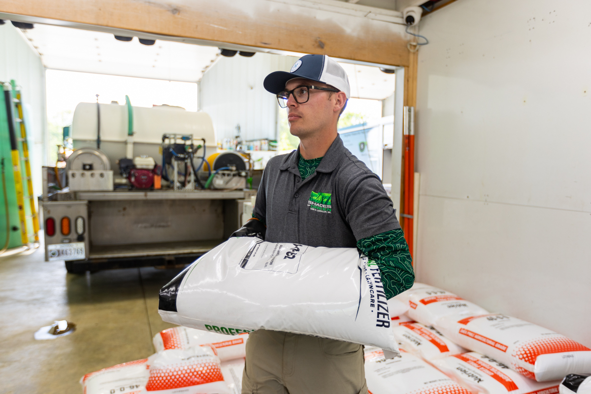Technician carrying a bag of fertilizer off a stacked pallet in the shop