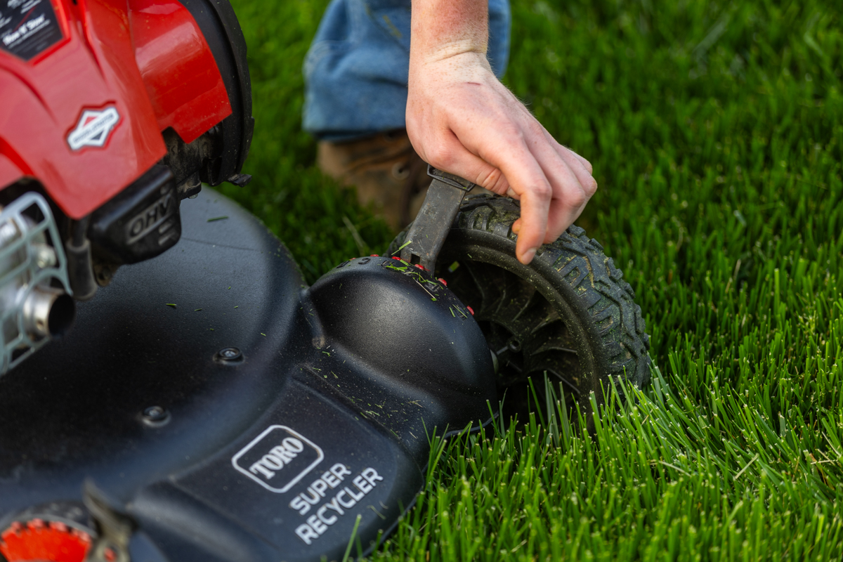 Close-up of a hand setting the cutting height on a Toro push mower