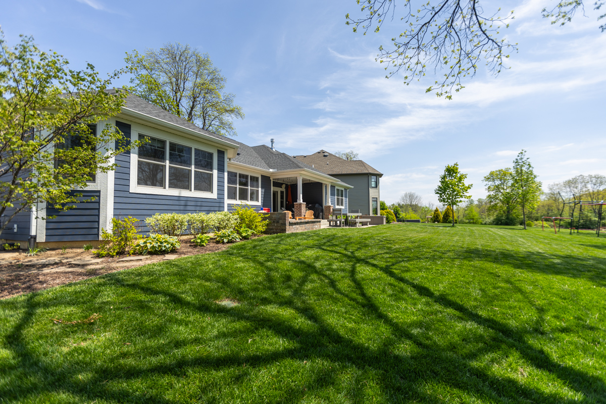 Wide green backyard lawn behind a blue-sided home