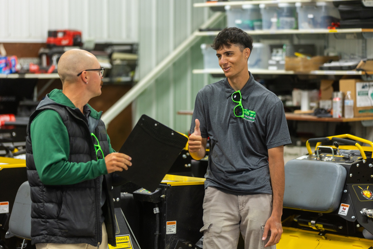 Two Shades of Green team members talking over a clipboard in the equipment shop