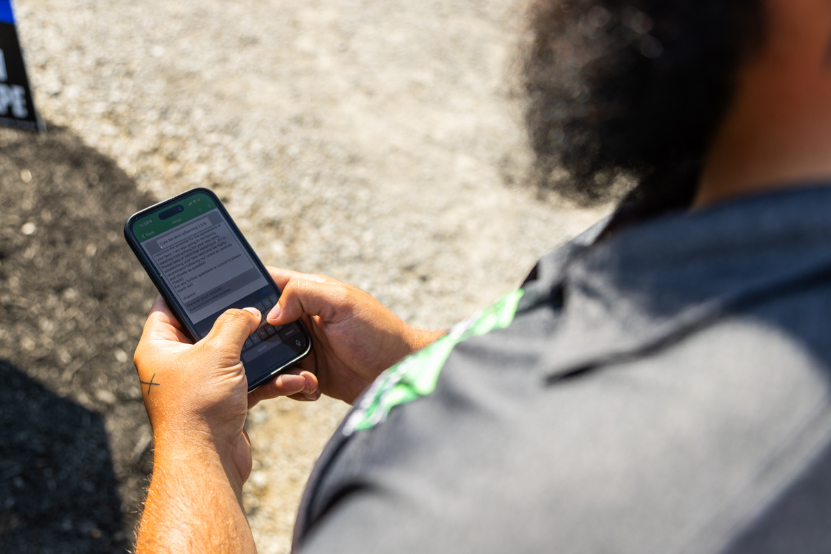 Close-up of a technician reading a service ticket on a phone