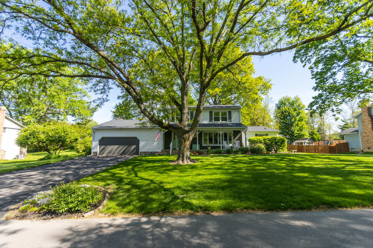 Front lawn shaded by a large tree in front of a two-story home